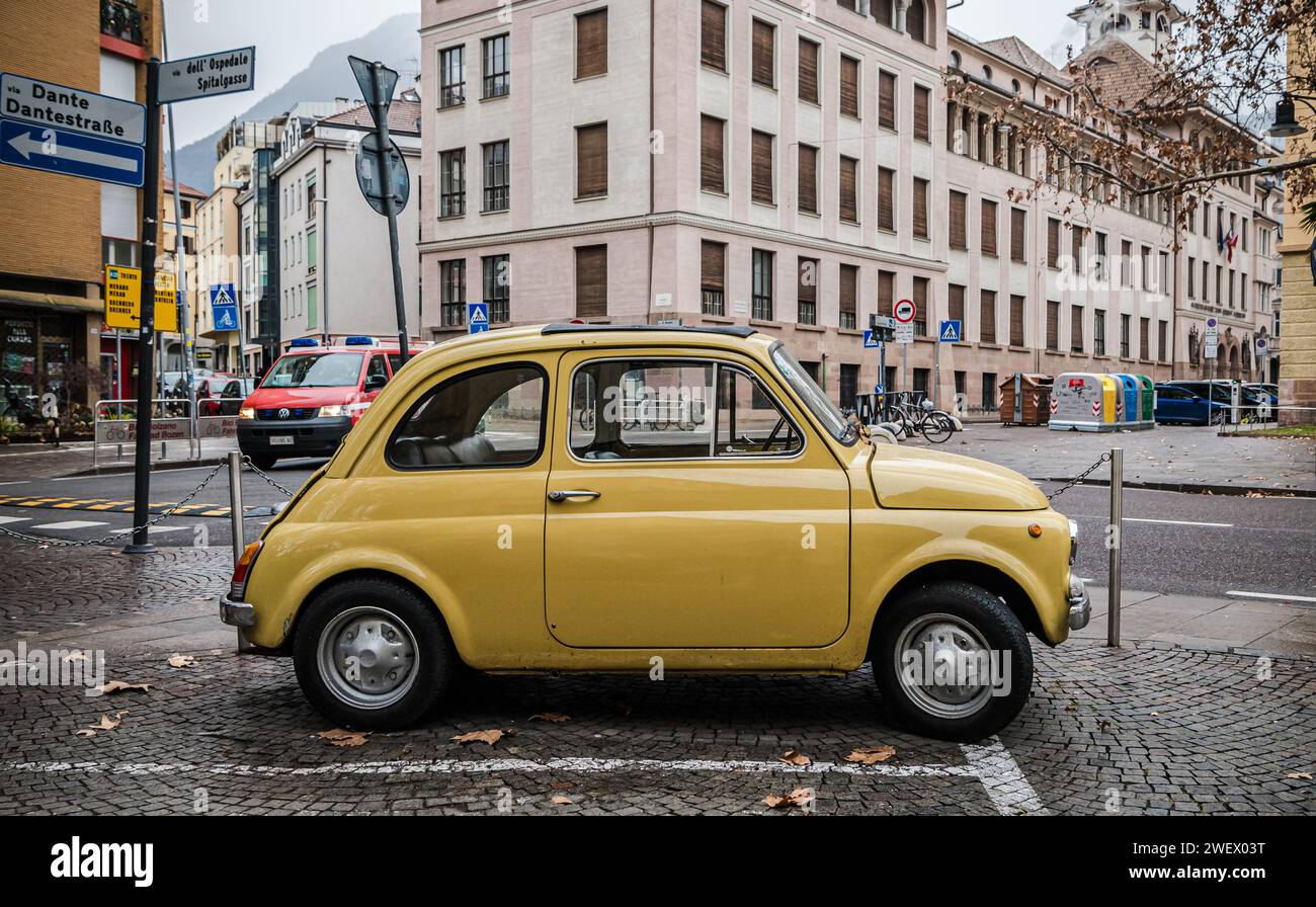 Vieille voiture classique jaune rétro Fiat 500 sur la rue de la ville de Bolzano dans le Tyrol du Sud, Trentin Haut-Adige, Italie du Nord, Europe. Banque D'Images