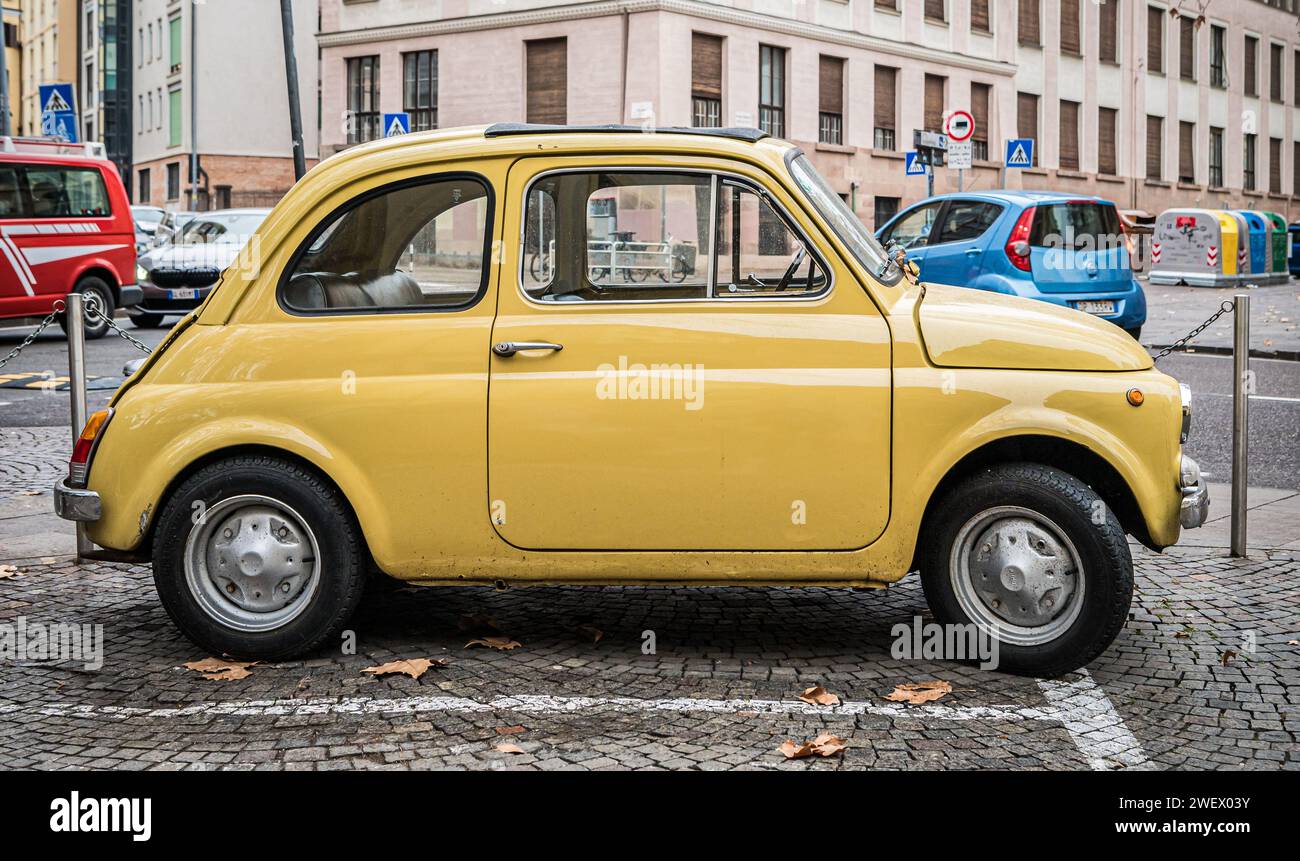 Vieille voiture classique jaune rétro Fiat 500 sur la rue de la ville de Bolzano dans le Tyrol du Sud, Trentin Haut-Adige, Italie du Nord, Europe. Banque D'Images