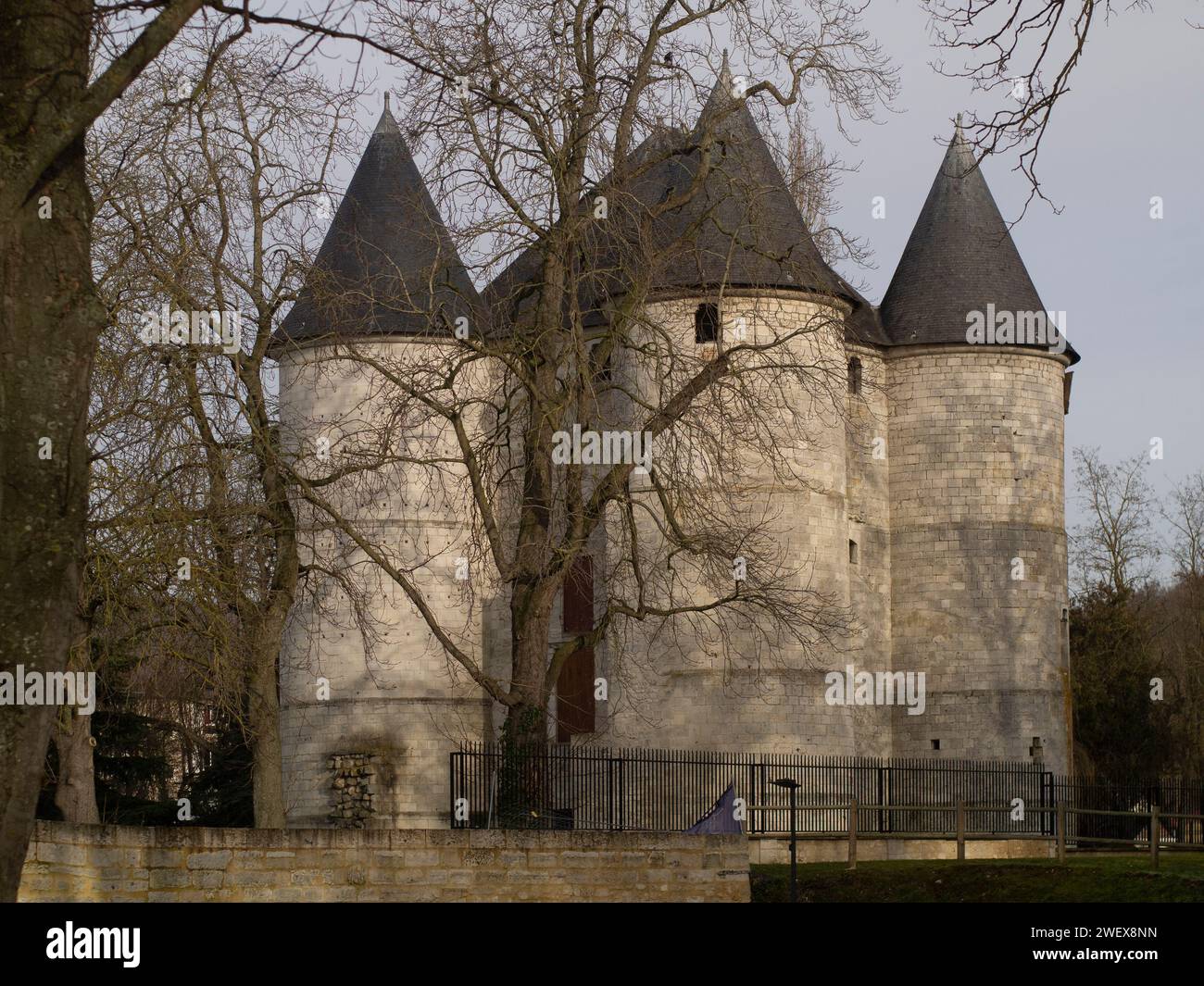 Château des tourelles à Vernon, Eure, France | Château médiéval en pierre avec tours jumelles entourées d'arbres, sous un ciel dégagé. Banque D'Images