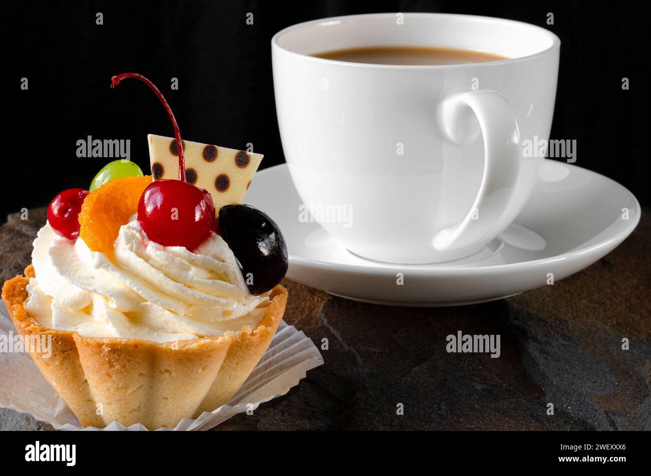 Gâteau sucré avec cerises et crème et une tasse de café. Dessert Banque D'Images