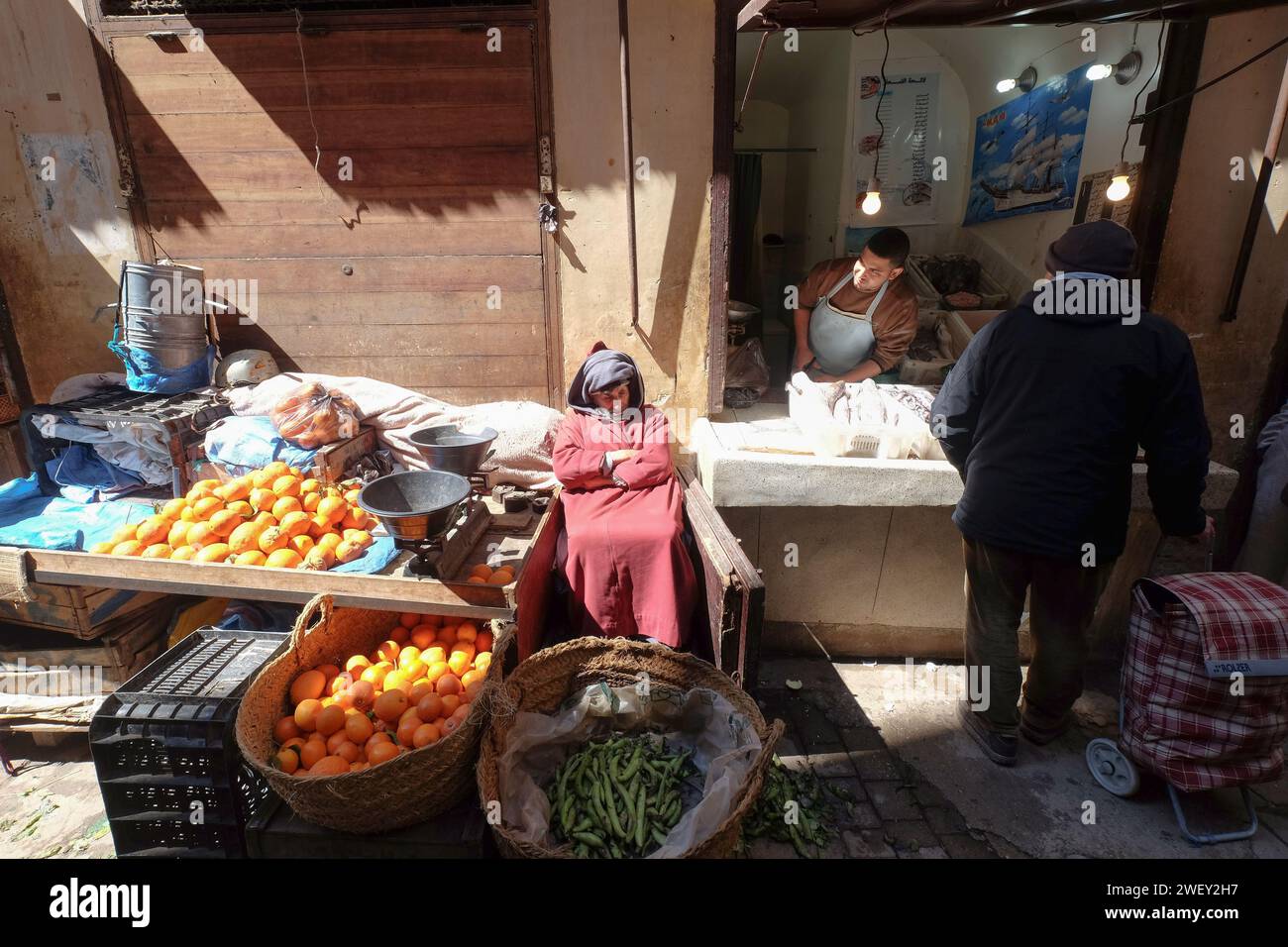 Vieil homme vendant des fruits et légumes dans le souk du marché en bordure de route dans la ville de Fès au Maroc. Commerces locaux sur la route. Banque D'Images