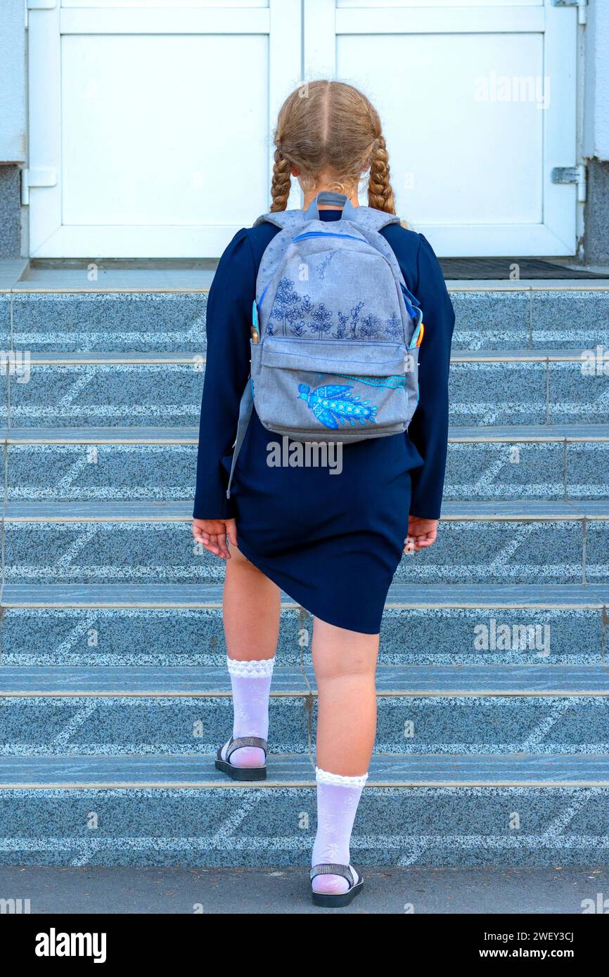 écolière sur le fond de l'école. Concept jours d'école, Retour à l'école. fille en uniforme avec un sac à dos. élève, apprenant, érudit.vue arrière Banque D'Images