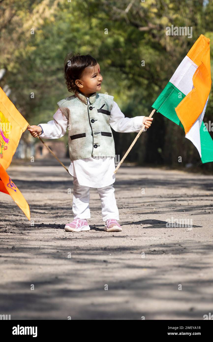 jeune enfant agitant le drapeau national tricolore indien et le drapeau safran sacré le jour à partir d'un angle plat Banque D'Images