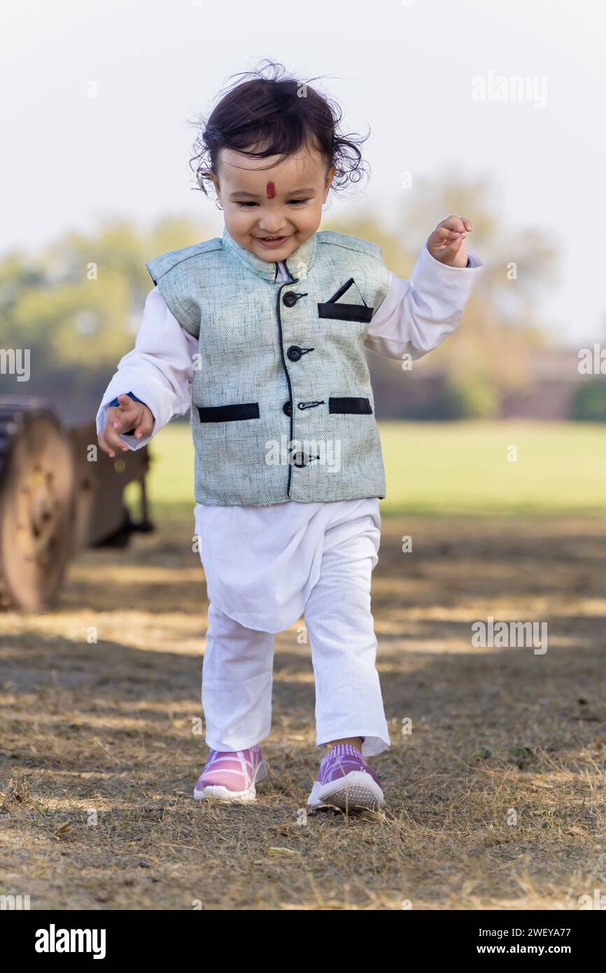 mignon enfant indien marchant à l'extérieur en robe traditionnelle le matin à partir d'angle plat Banque D'Images