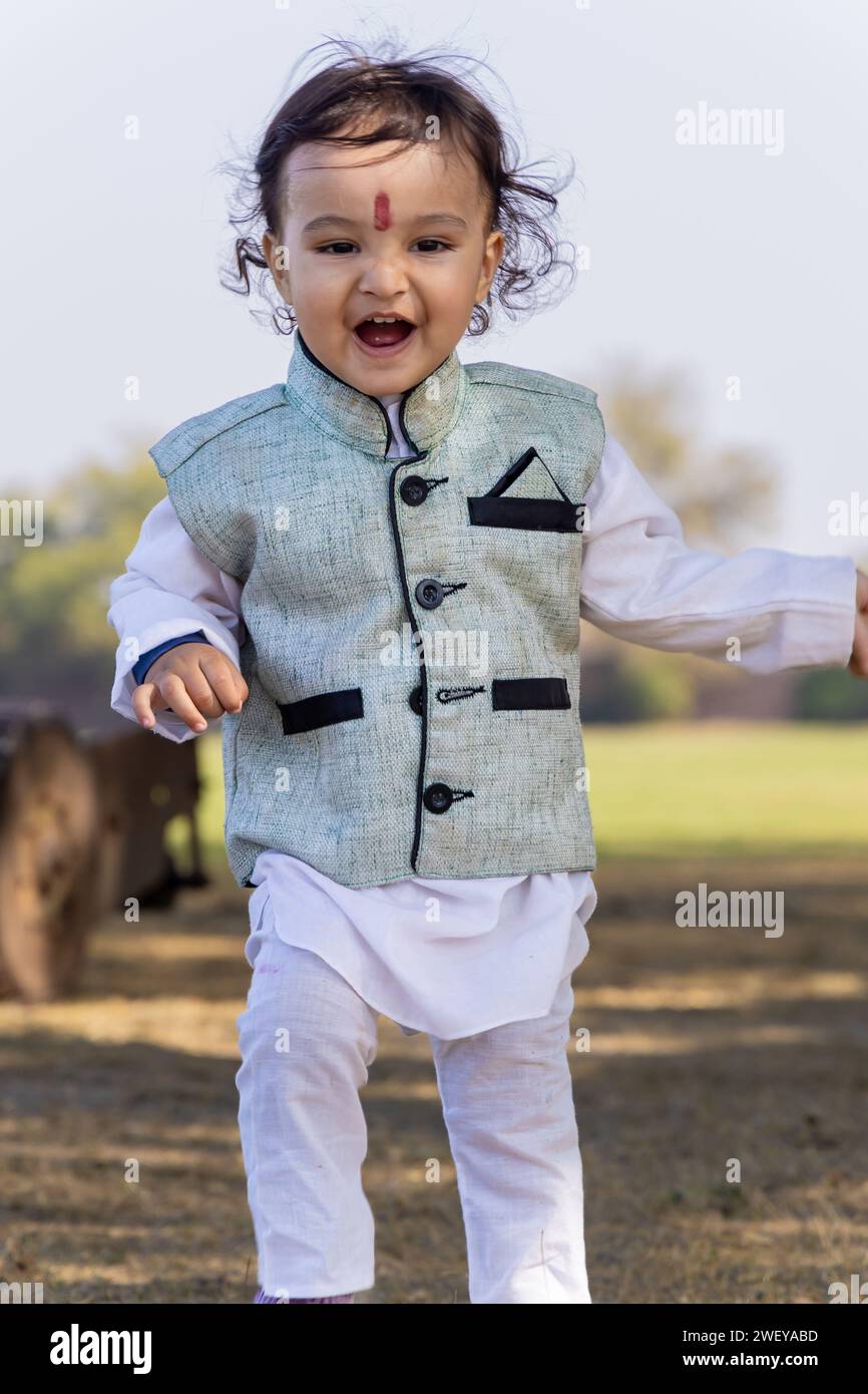 mignon enfant indien marchant à l'extérieur en robe traditionnelle le matin à partir d'angle plat Banque D'Images