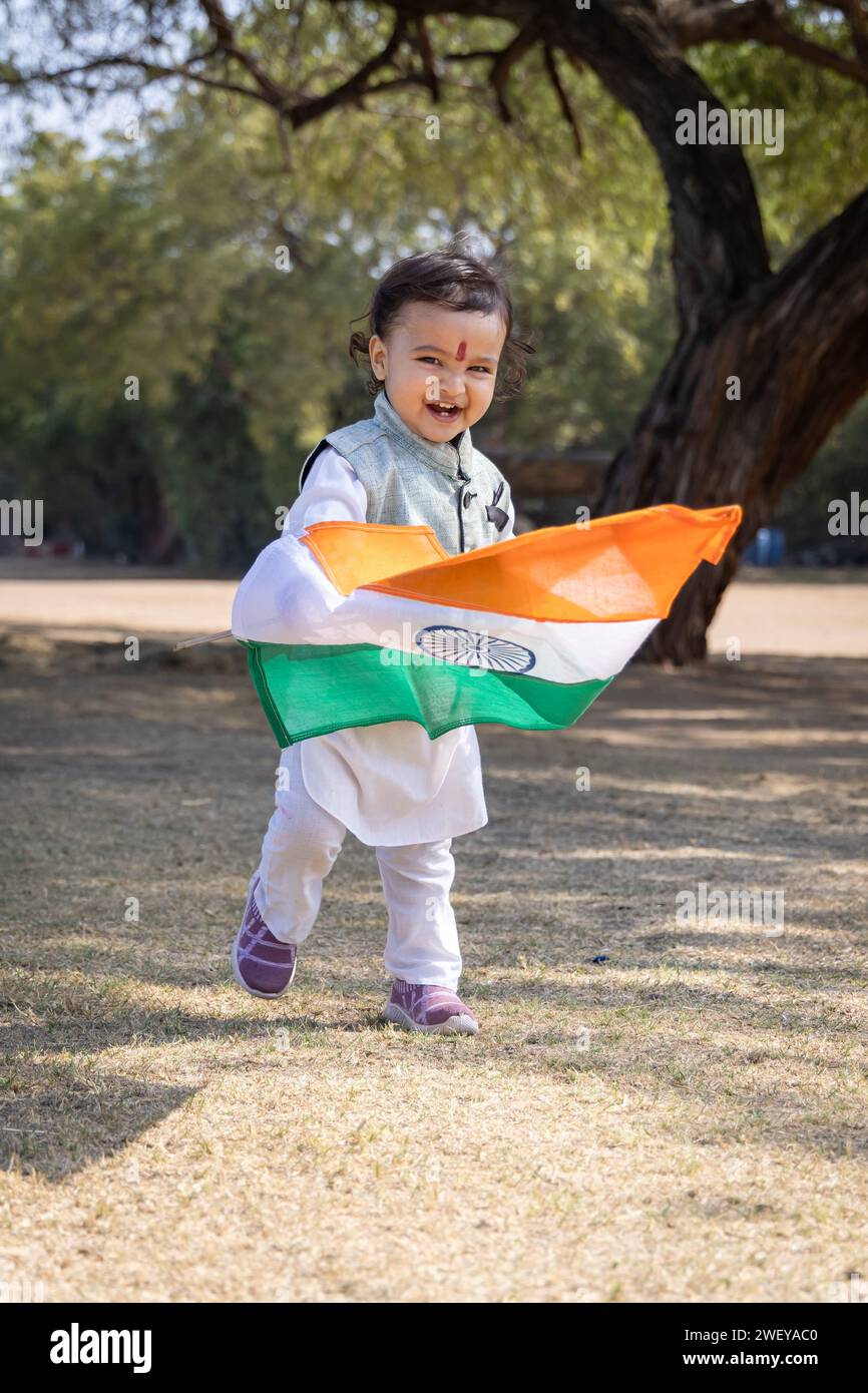 mignon enfant indien avec drapeau national indien marchant à l'extérieur en robe traditionnelle le matin Banque D'Images