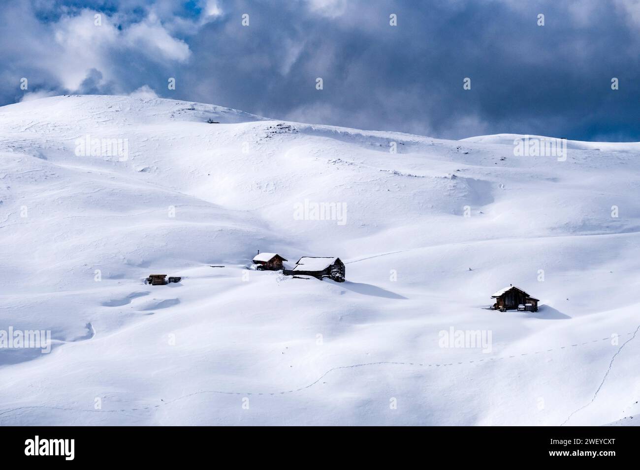 Quelques maisons en bois enneigées sur les pentes du Passo Sella passent en hiver. Banque D'Images