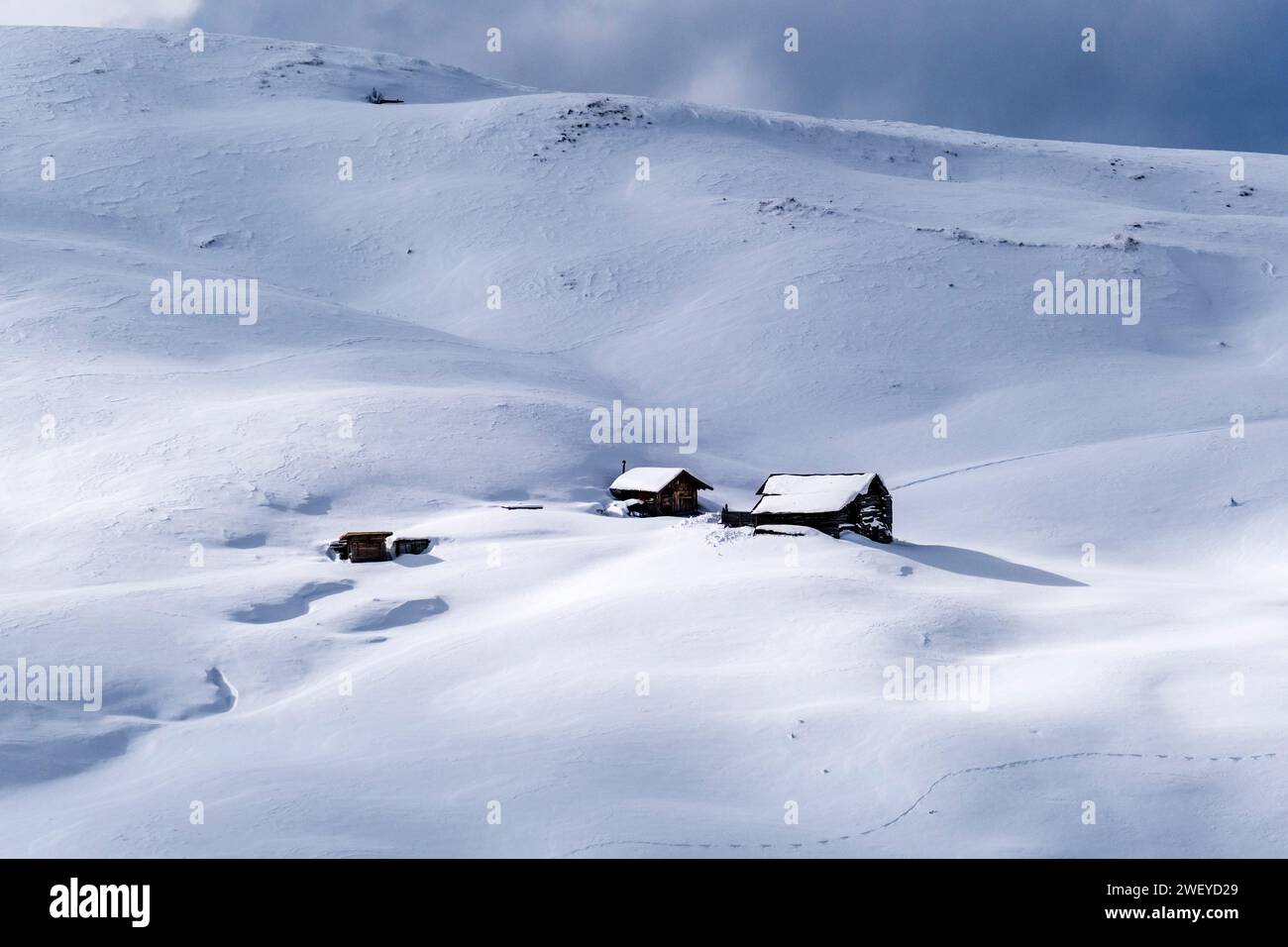 Quelques maisons en bois enneigées sur les pentes du Passo Sella passent en hiver. Banque D'Images