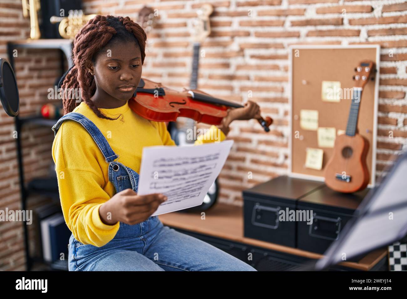 Femme africaine américaine musicienne jouant du violon regardant une feuille de musique dans un studio de musique Banque D'Images