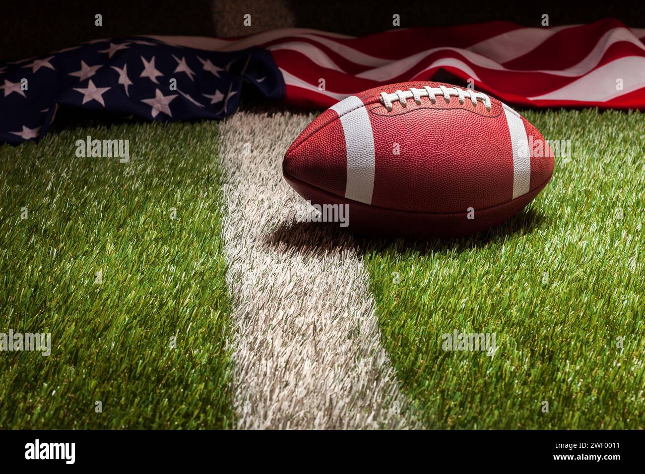 Un drapeau de football et américain sur le terrain d'herbe avec rayure dans la lumière dramatique Banque D'Images