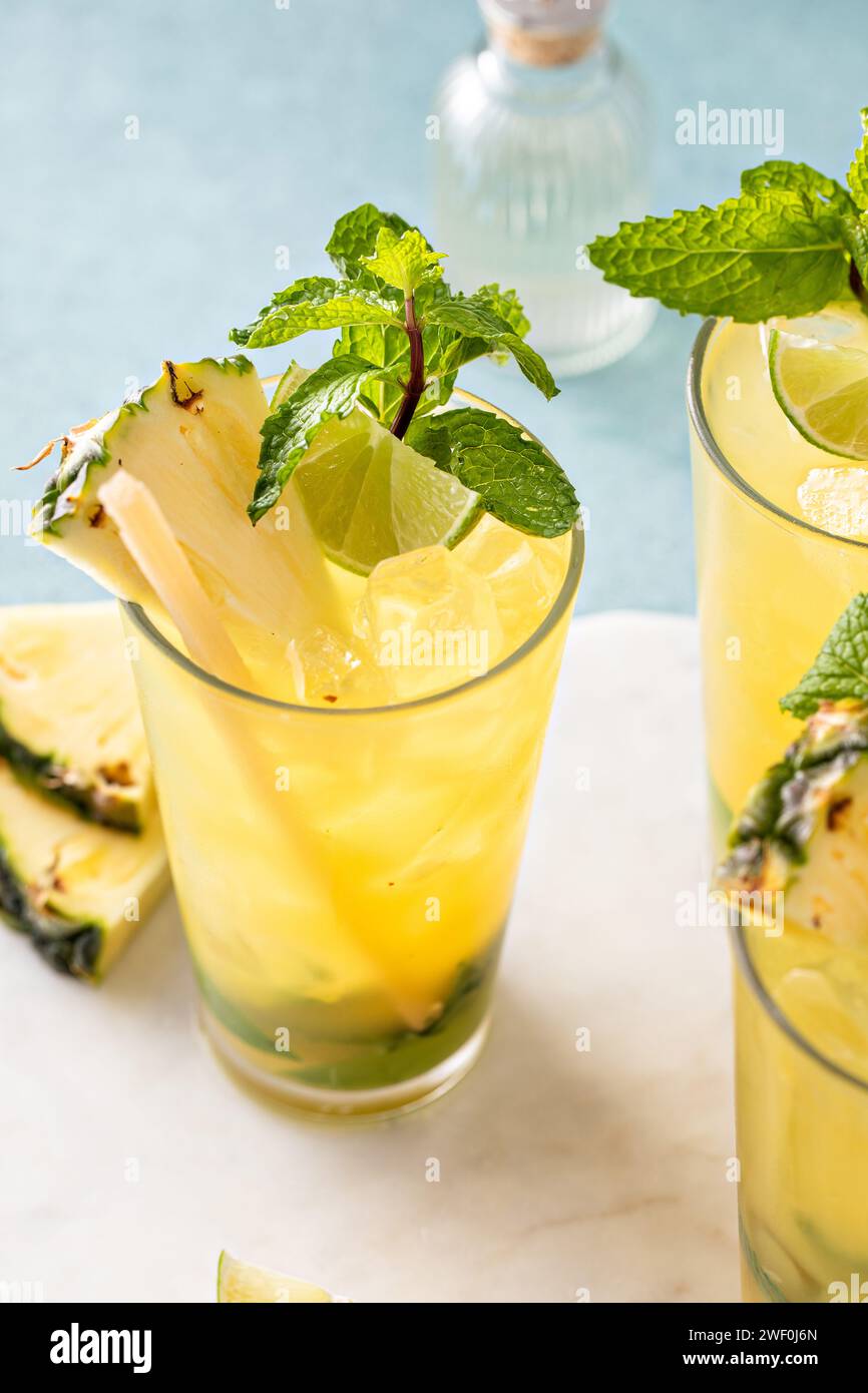 Mojito ananas à la menthe boueuse et citron vert servi avec un bâton de canne à sucre Banque D'Images