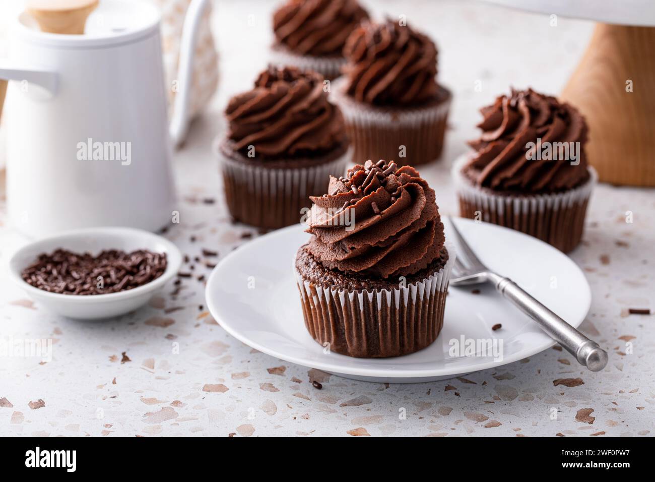 Cupcakes au chocolat garnis de ganache au chocolat fouettée et de saupoudreuses de chocolat Banque D'Images