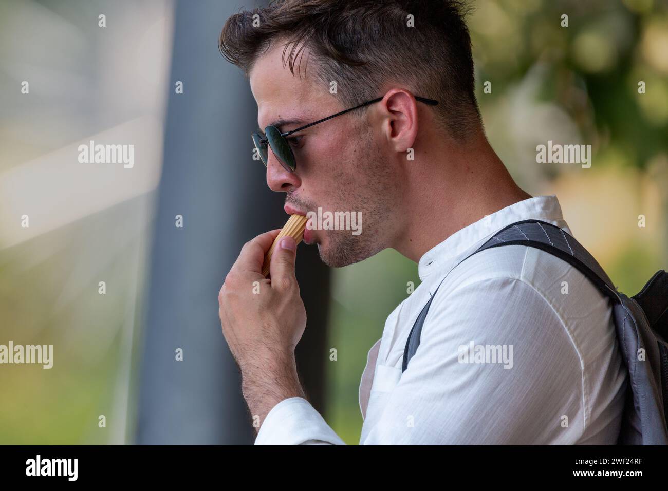 Un homme en lunettes de soleil mangeant un cornet de crème glacée en Lombardie, Italie. Banque D'Images