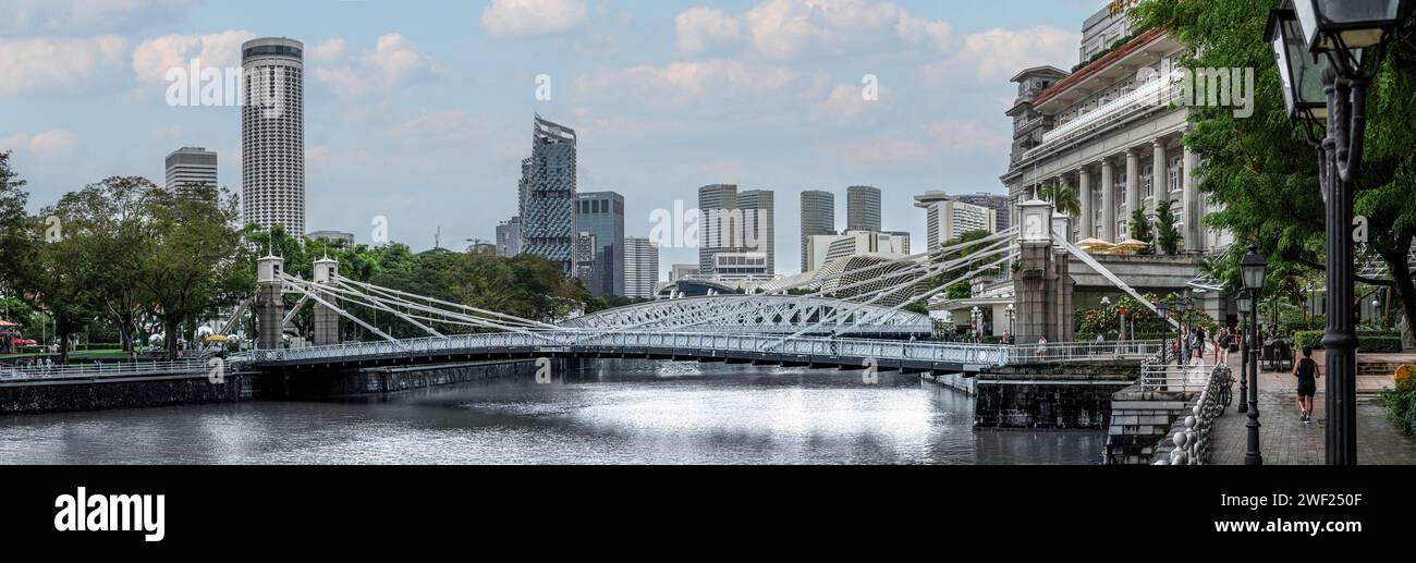 Singapour, le 24 janvier 2024 : le pont Cavenagh s'étend élégamment sur le fleuve Singapour, l'emblématique Fullerton Hotel et d'imposants gratte-ciel. architectural Banque D'Images