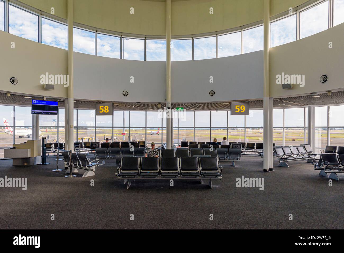 Un salon d'attente dans le terminal domestique 2 de l'aéroport de Sydney, avec vue à travers de grandes fenêtres sur la piste, Sydney, Nouvelle-Galles du Sud, Australie Banque D'Images