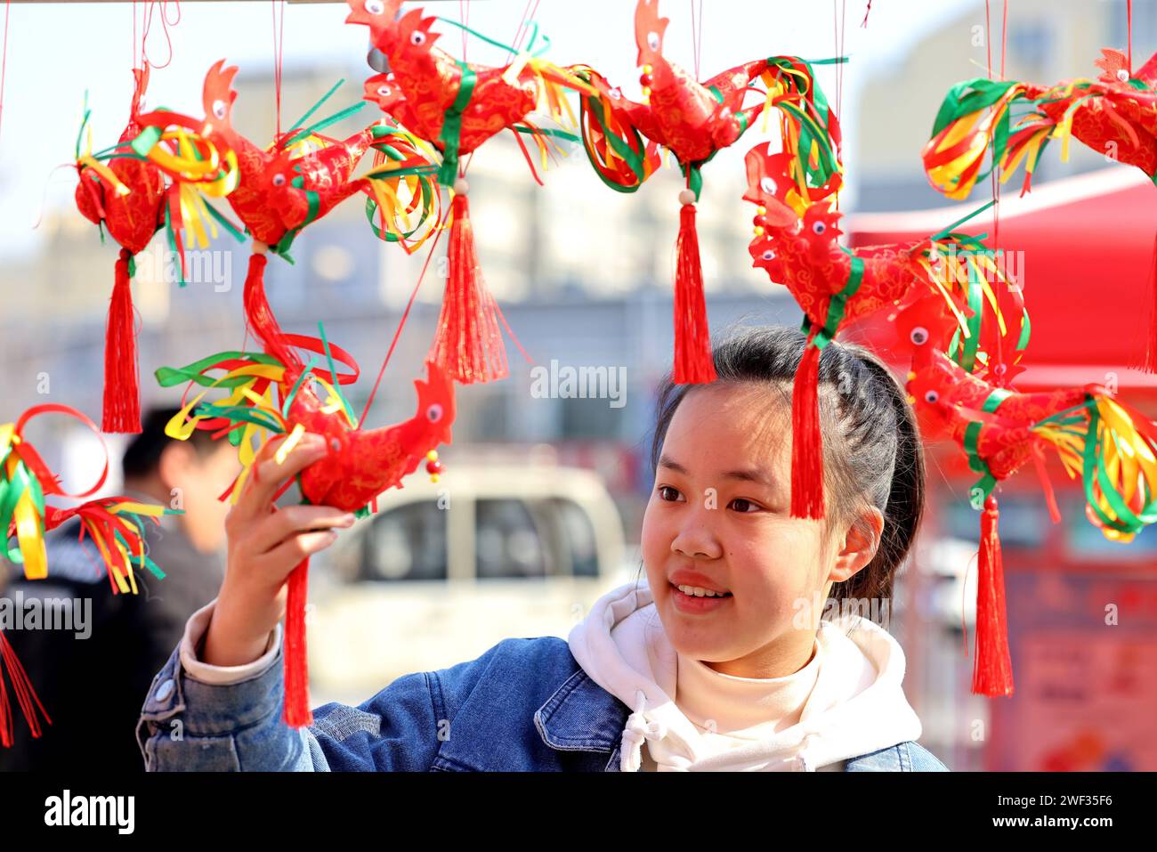 Zaozhuang, Chine. 28 janvier 2024. Une fille sélectionne un ''poulet printanier'' cousu à la main par un artiste folklorique lors d'une foire commerciale du nouvel an à Zaozhuang, dans la province du Shandong, en Chine, le 28 janvier 2024. (Photo Costfoto/NurPhoto) crédit : NurPhoto SRL/Alamy Live News Banque D'Images