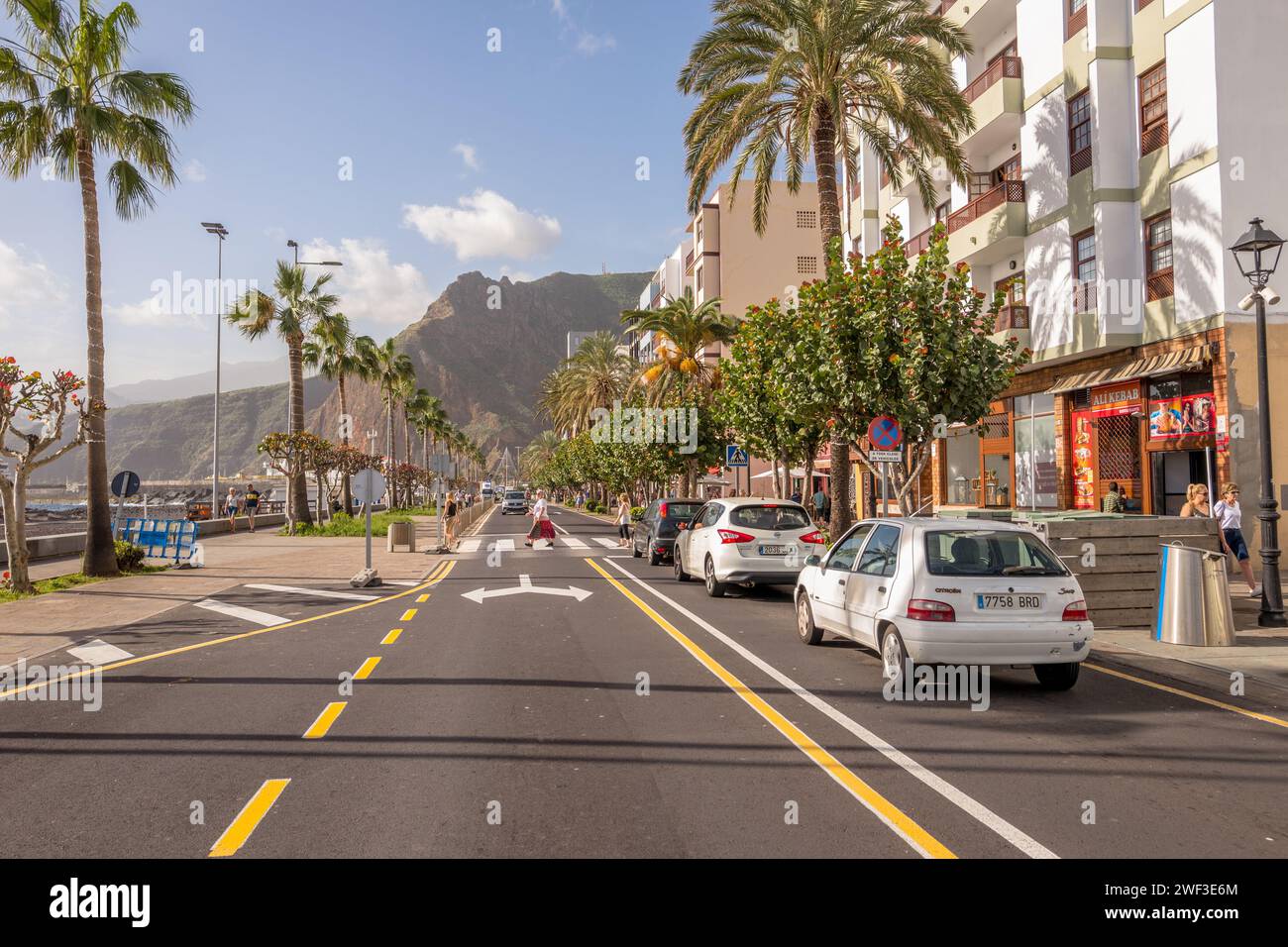 Les gens traversant l'avenue maritime bordée de palmiers principale ou la route côtière sur l'île Canaries de la Palma. Banque D'Images