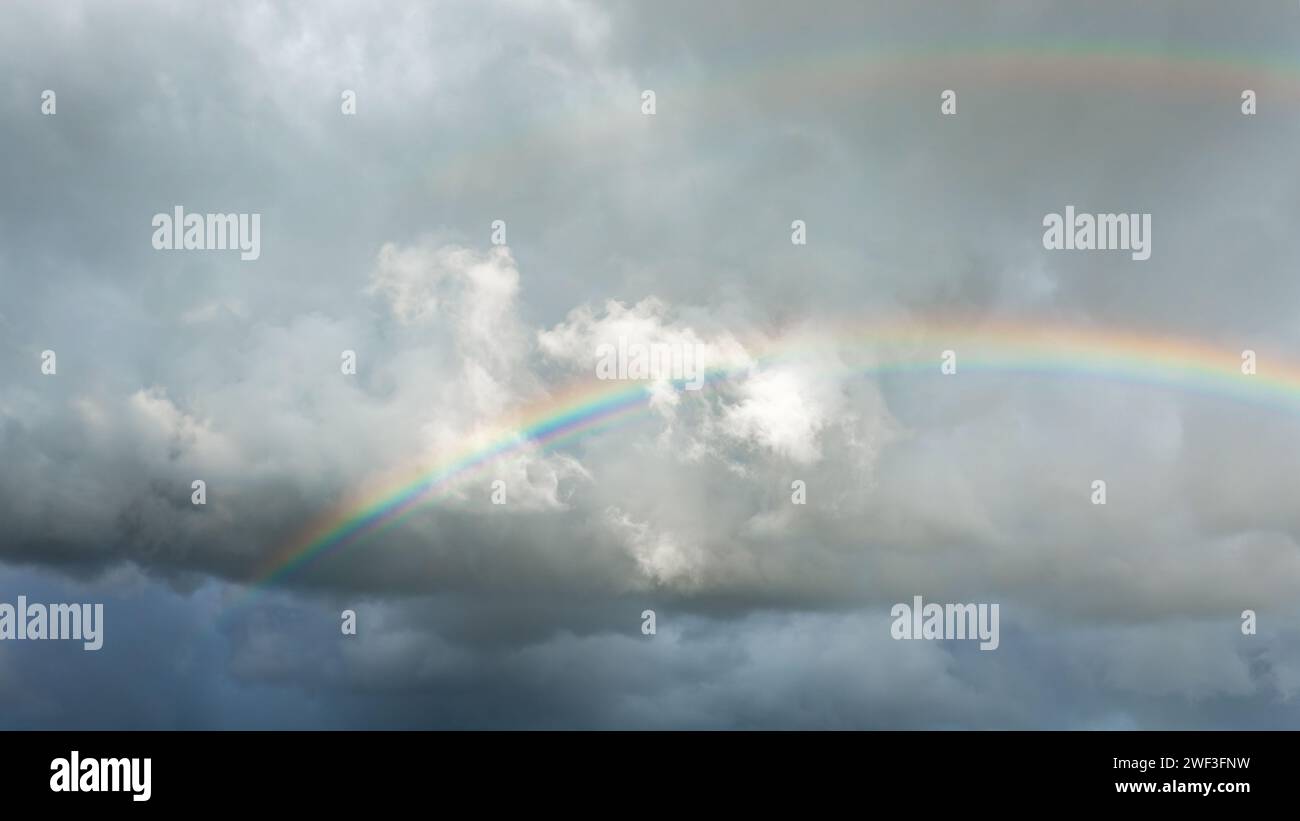 Un double arc-en-ciel dans un ciel nuageux, orageux et gris. Banque D'Images