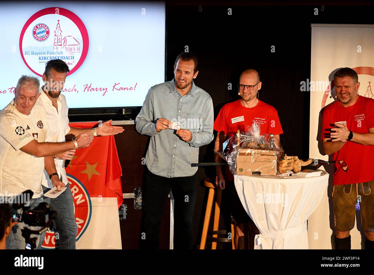 Kirchweidach, Allemagne. 28 janvier 2024. Football : Bundesliga, FC Bayern Munich. Le joueur du FC Bayern Harry Kane d'Angleterre se tient sur une scène avec des fans au fan club 'Die Roten' à Kirchweidach. Il a reçu un trophée pour sa victoire dans un mini-olympique bavarois sous la forme d'une couronne de buteur de buts, qu'il pouvait également utiliser pour profiter du tabac à priser. Les stars du FC Bayern ont compensé leurs visites au fan club, qui avaient été reportées en décembre en raison de la météo hivernale. Crédit : -/Jens Niering/dpa/Alamy Live News Banque D'Images