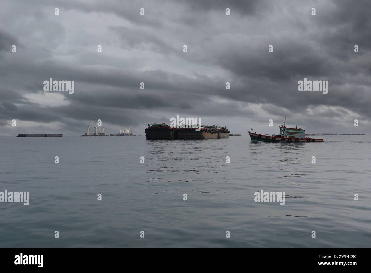 Remorqueurs et cargos amarrés dans la baie de Koh Sichang, province de Chonburi en Thaïlande, ciel couvert et pluie venant. Banque D'Images