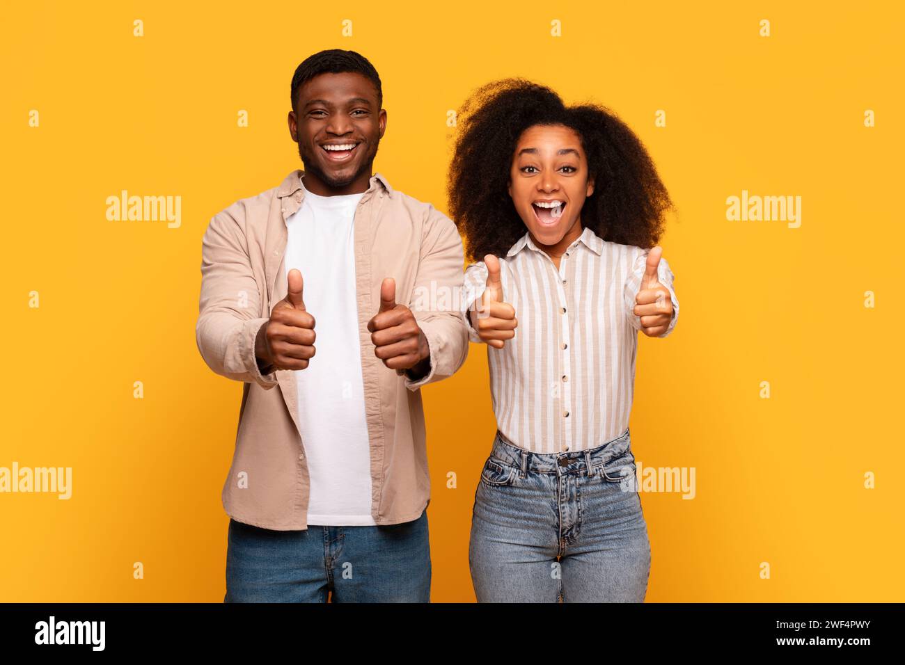 Couple noir excité donnant les pouces ensemble sur fond jaune Banque D'Images