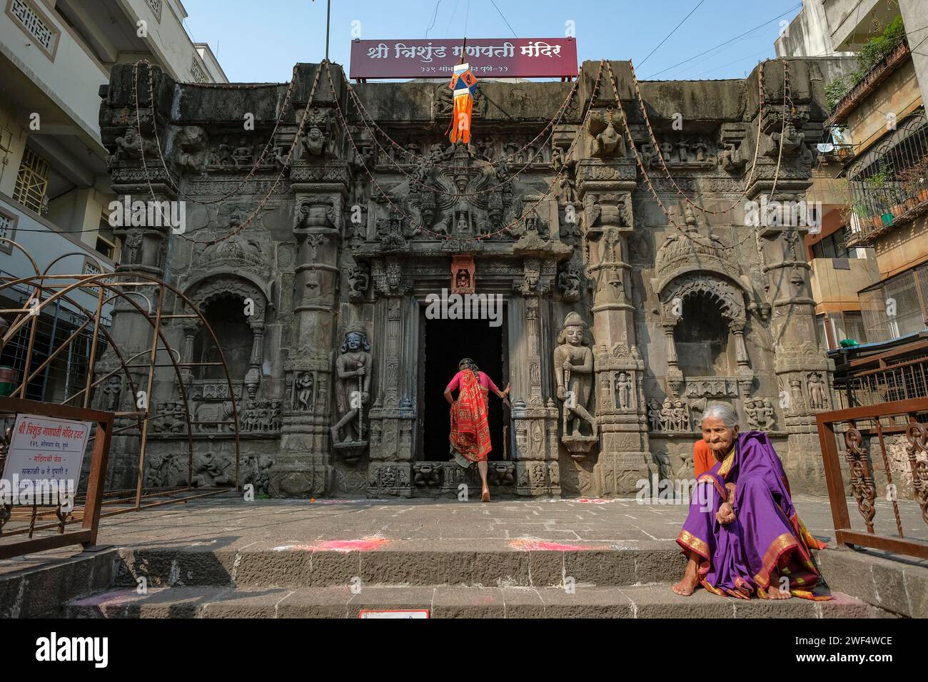 Pune, Inde - 27 janvier 2024 : une femme est assise sur les marches du temple Trishunda Ganpati à Pune, en Inde. Banque D'Images