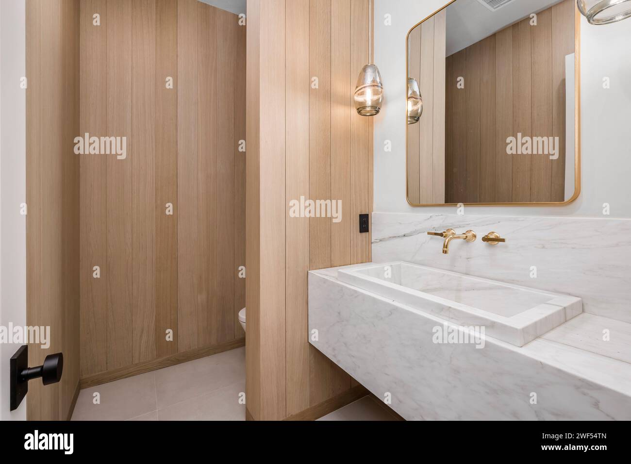Salle de bains élégante dotée d''une armoire en bois et d''un lavabo en marbre sur une élégante coiffeuse en bois Banque D'Images