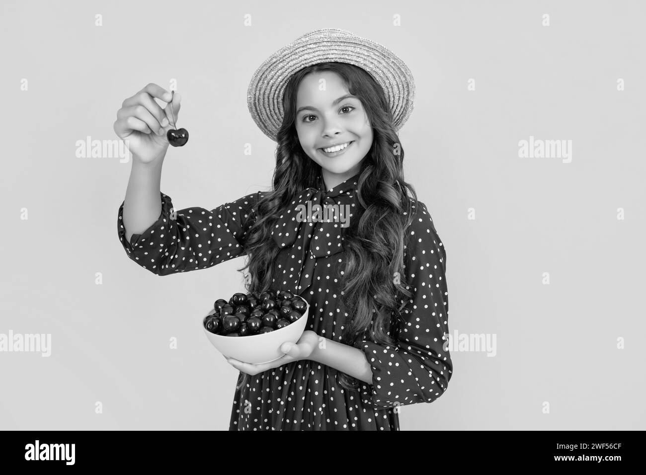 bonne fille de l'adolescence tenir bol de cerise sur fond jaune Banque D'Images