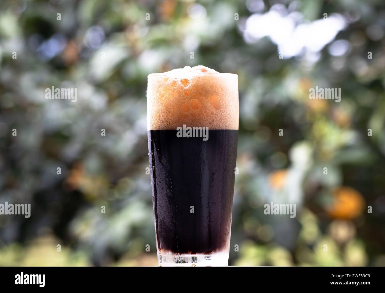 Boisson sombre et orange en grand verre sur une table en bois Banque D'Images