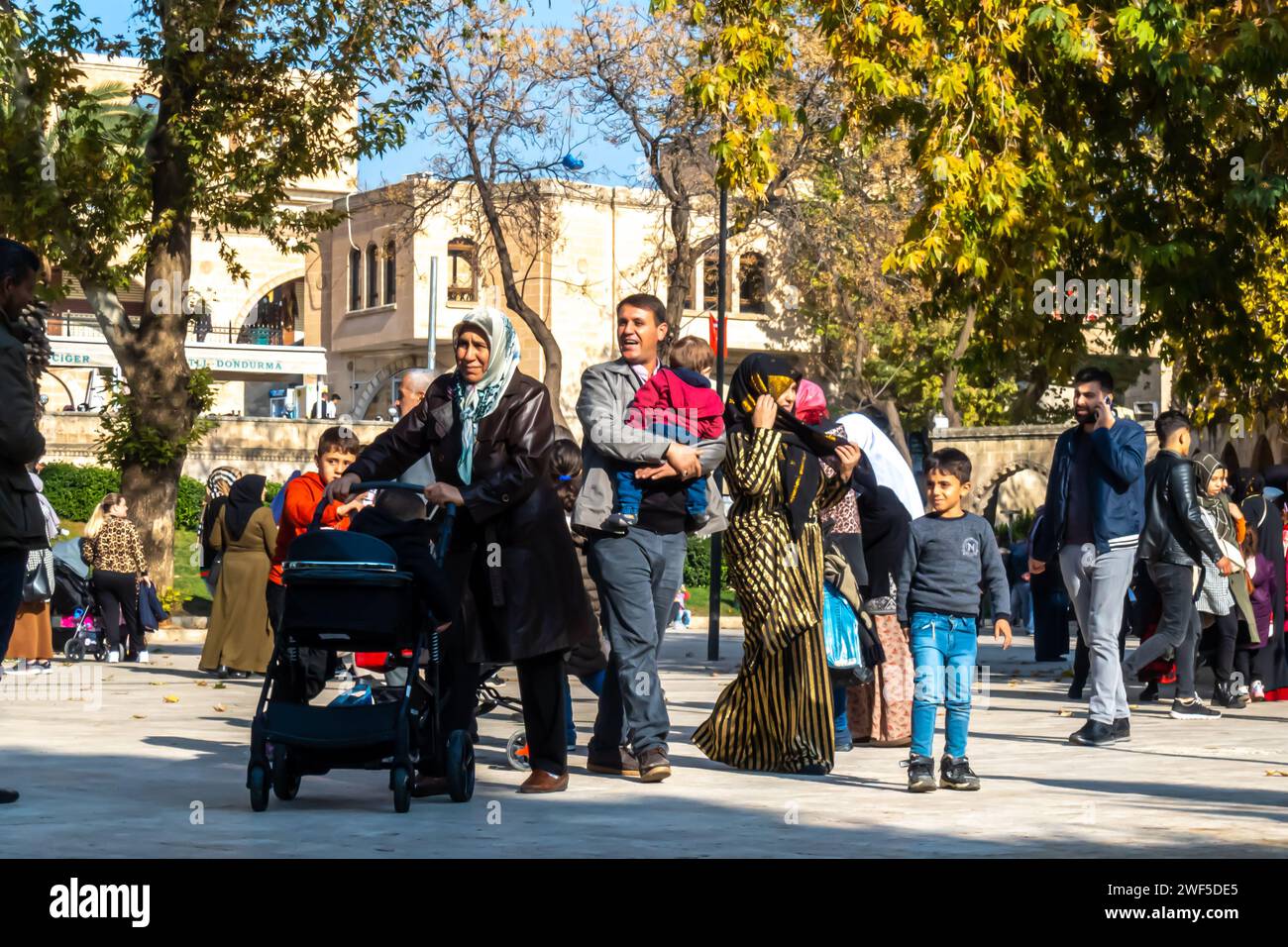 Famille de personnes avec un enfant, enfants, traversant la rue dans le centre d'Urfa Sanliurfa Sud-est de la Turquie Banque D'Images