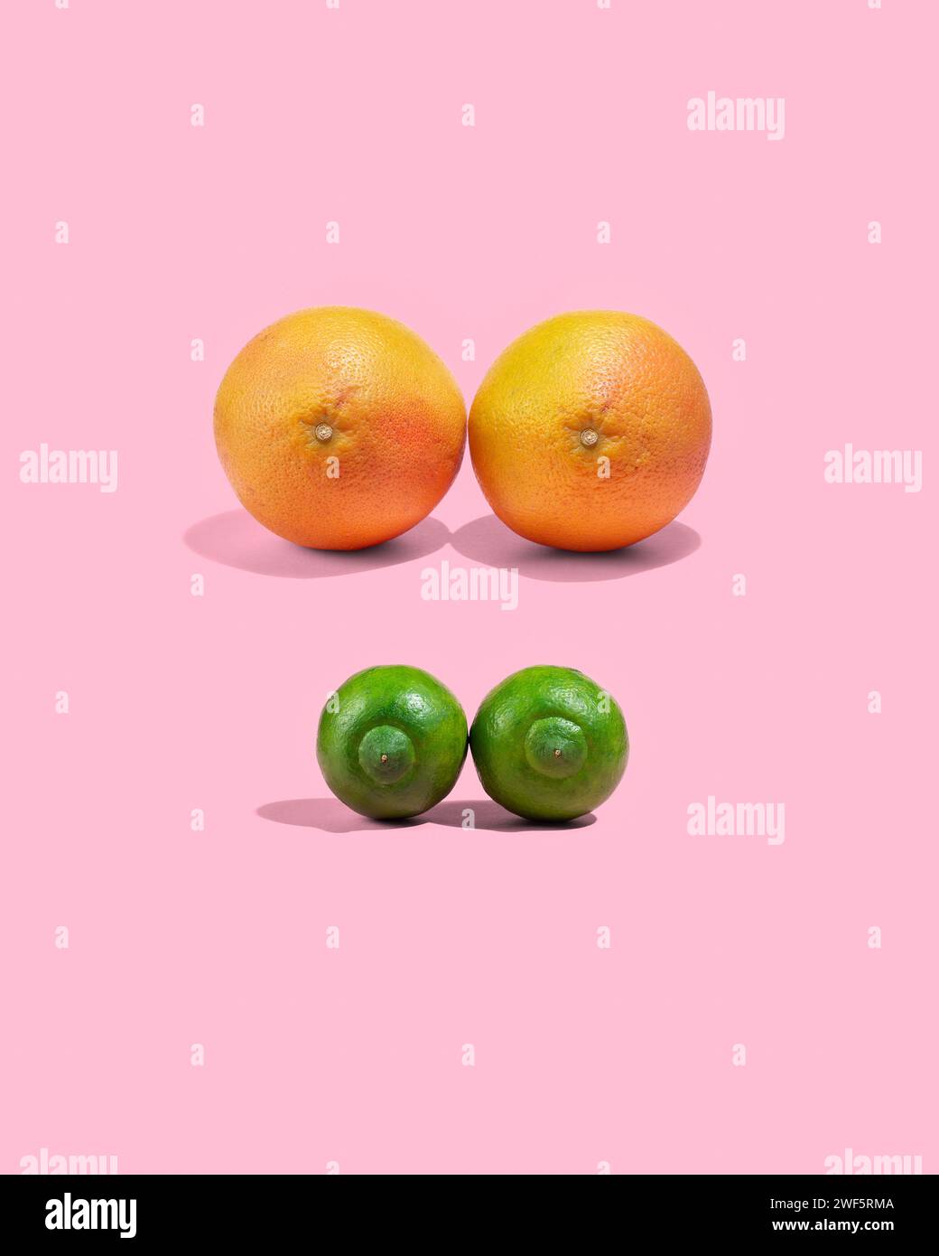 Oranges et citrons crus sur fond rose, concept de seins féminins de différentes tailles, pas de gens Banque D'Images