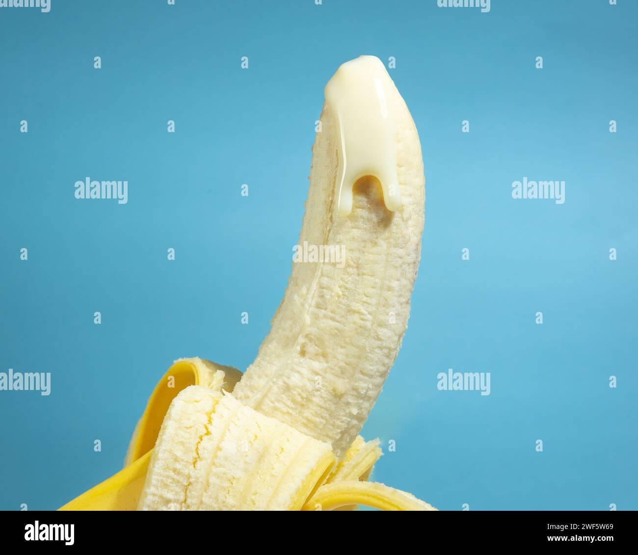 Banane avec peau et laitière sur fond bleu, concept de pénis masculin, éducation sexuelle de santé, pas de gens Banque D'Images
