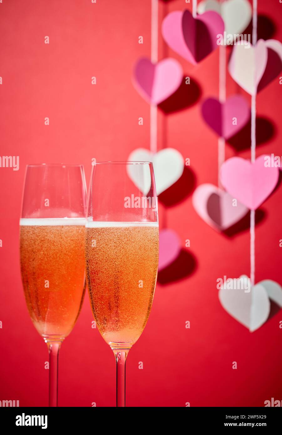 deux verres de champagne et décoration en forme de coeur défocalisé sur fond rouge Banque D'Images