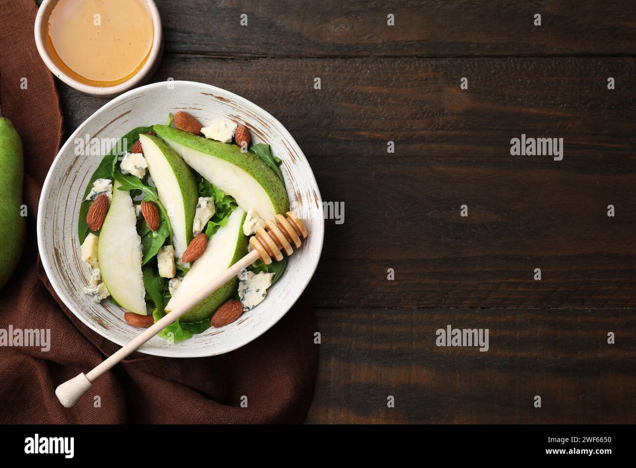 Délicieuse salade de poires dans un bol, miel et plongeur sur une table en bois, vue de dessus. Espace pour le texte Banque D'Images