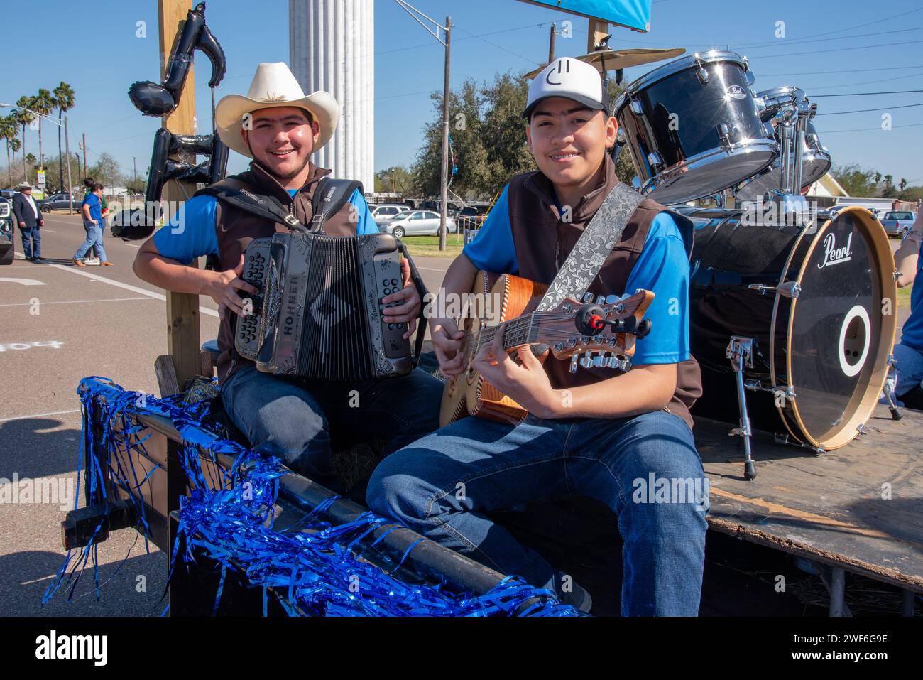 Deux garçons souriants jouant de la musique sur un accordéon et de la guitare sont assis sur un char à la 92e édition annuelle du Texas Citrus Fiesta's Parade of Oranges, Mission, Texas, USA. Banque D'Images