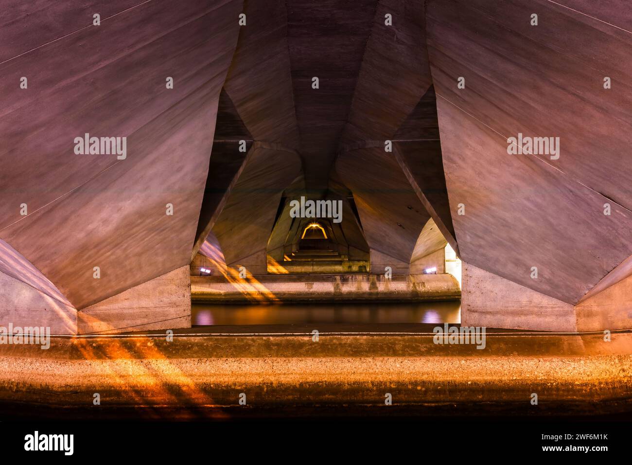 Lumières symétriques dorées sous un pont en béton moderne sur une rivière Banque D'Images