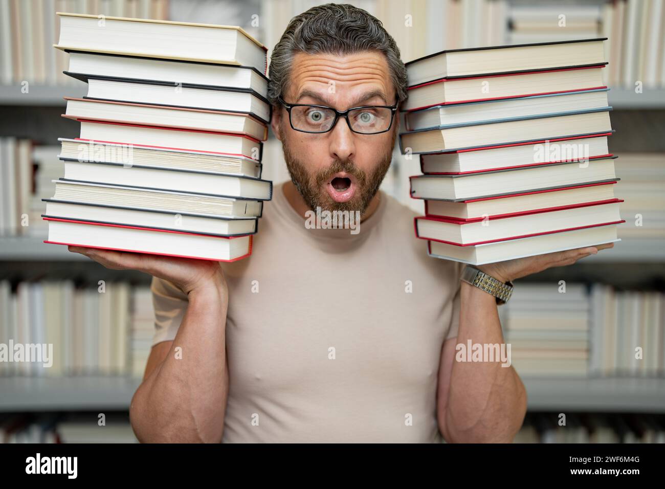 Journée des enseignants. Professeur drôle tenir beaucoup de livres. Professeur fou avec des livres. Professeur excité dans la bibliothèque de livres de l'école. Professeur de l'examen universitaire. Collège Banque D'Images