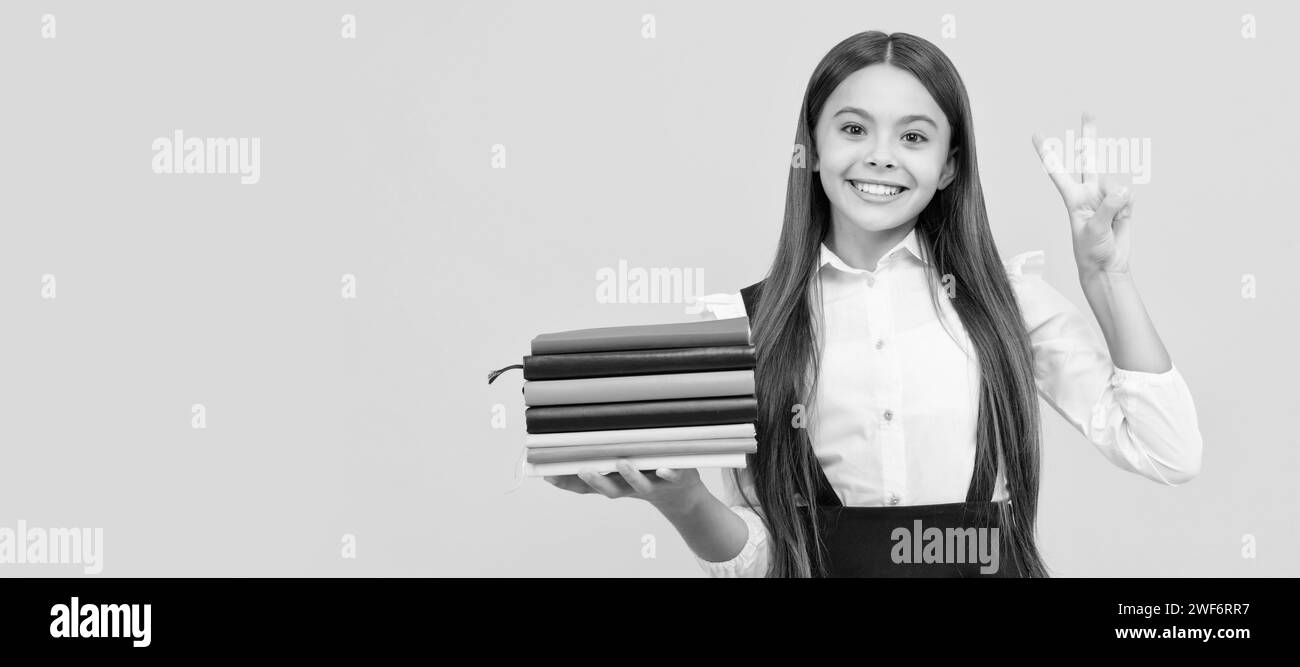 heureuse adolescente dans l'uniforme scolaire tenir la pile de livres montrent geste de paix, éducation. Portrait d'écolière étudiante, en-tête de bannière de studio. Écolier fa Banque D'Images