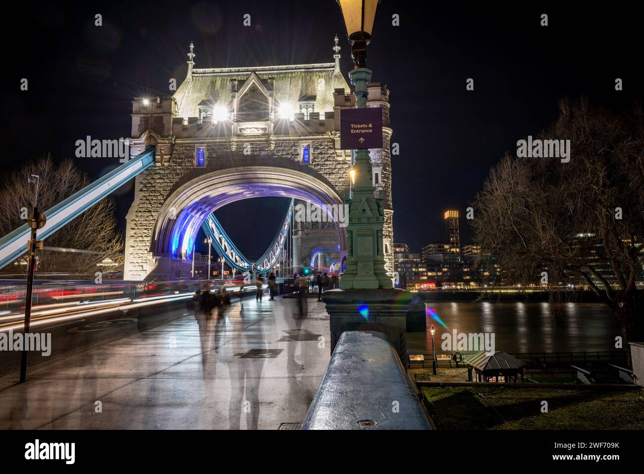 Une nuit, longue exposition photographiée sur Tower Bridge avec des piétons, des touristes visitant ce monument emblématique et des sentiers légers de passage des véhicules. Banque D'Images