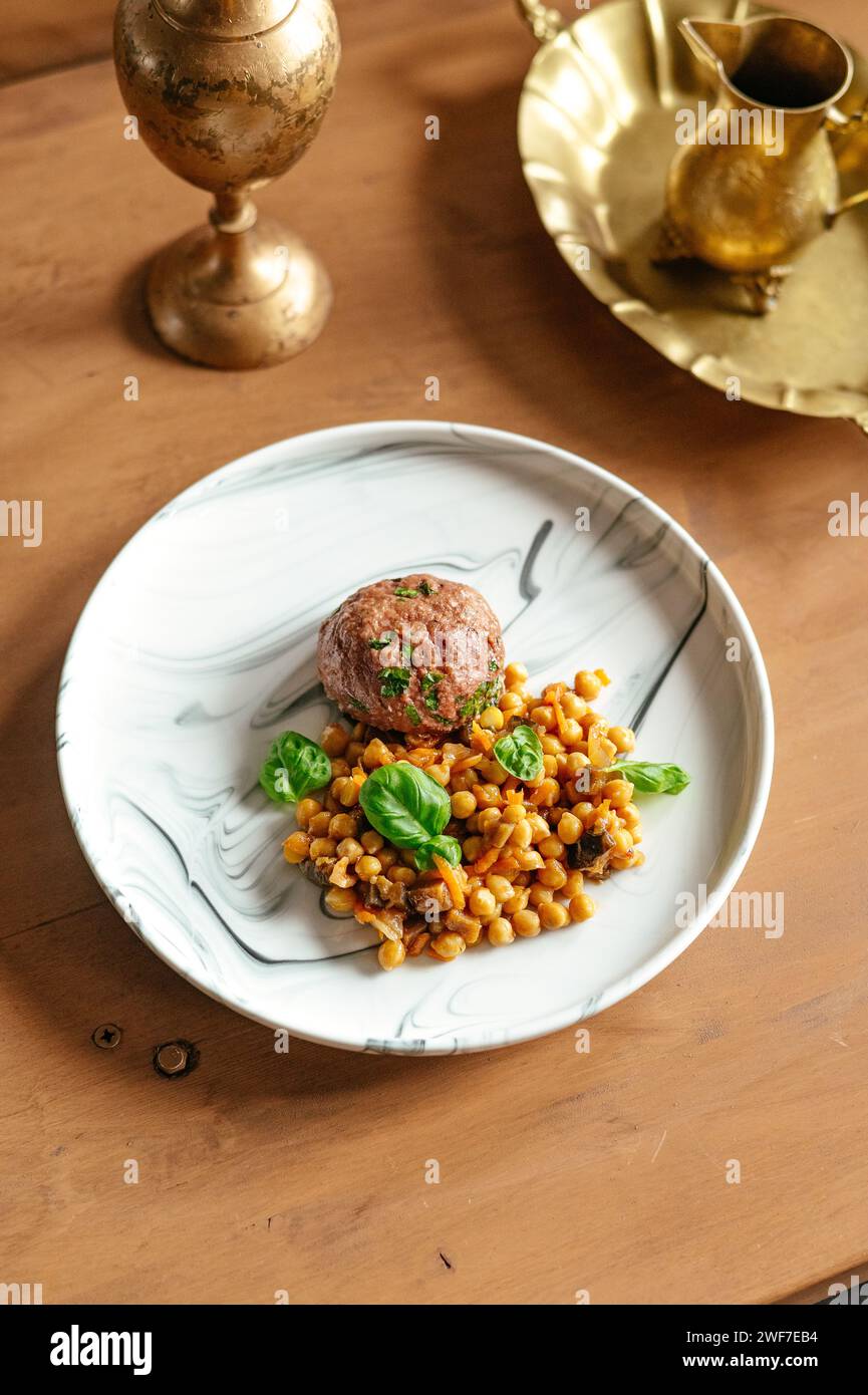 patty de boeuf sur une assiette avec un plat d'accompagnement de pois chiches et sauce Banque D'Images