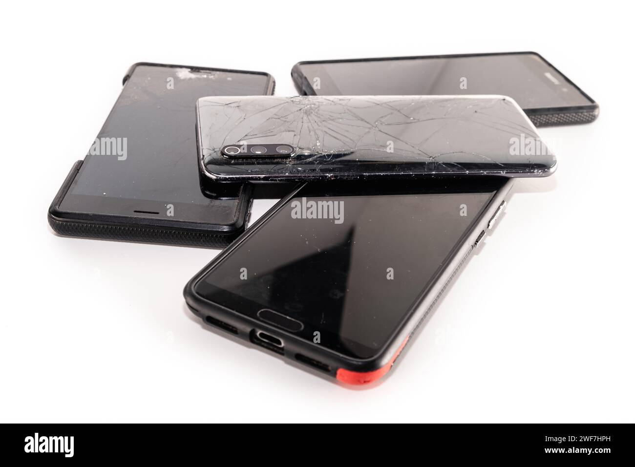 Pile de smartphones cassés isolé sur fond blanc. Téléphones portables endommagés avec écran fissuré. Banque D'Images