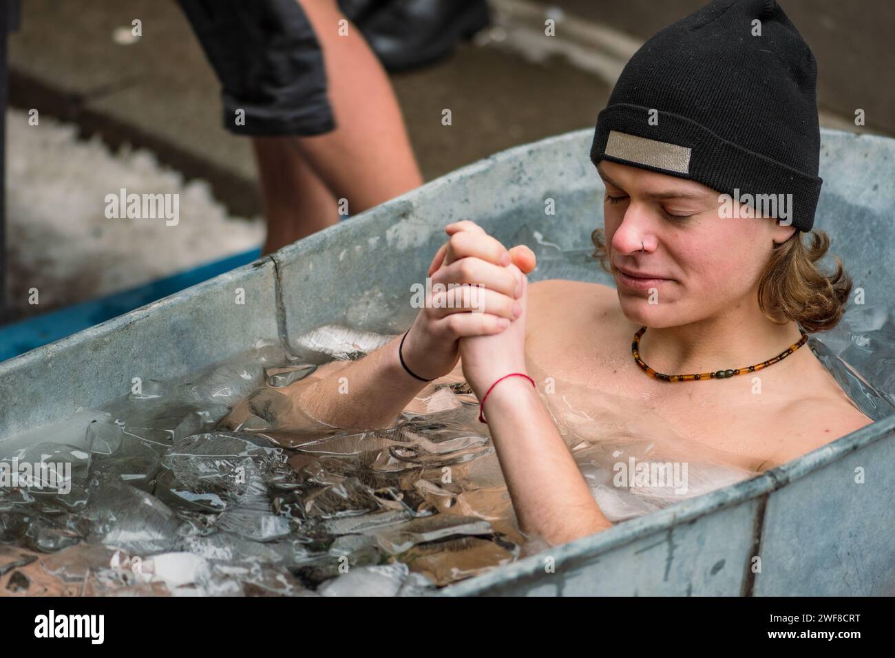 Beau garçon bain de glace dans l'eau froide parmi les glaçons dans une baignoire vintage. Méthode Wim Hof, thérapie par le froid, techniques respiratoires, méditation Banque D'Images