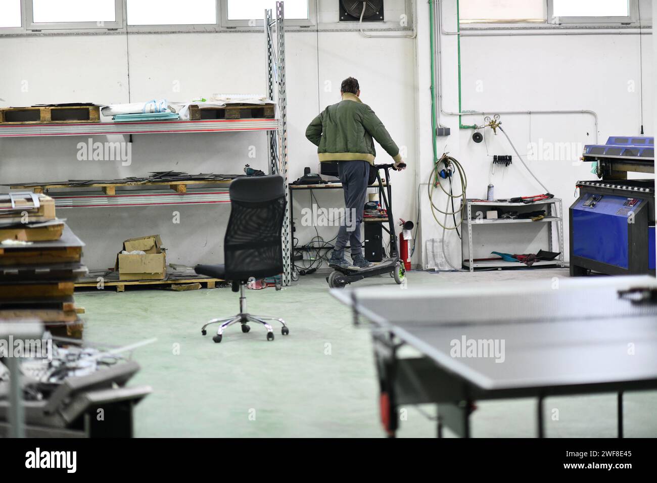 ingénieur dans un atelier de réparation électronique conduit scooter électrique dans une usine Banque D'Images