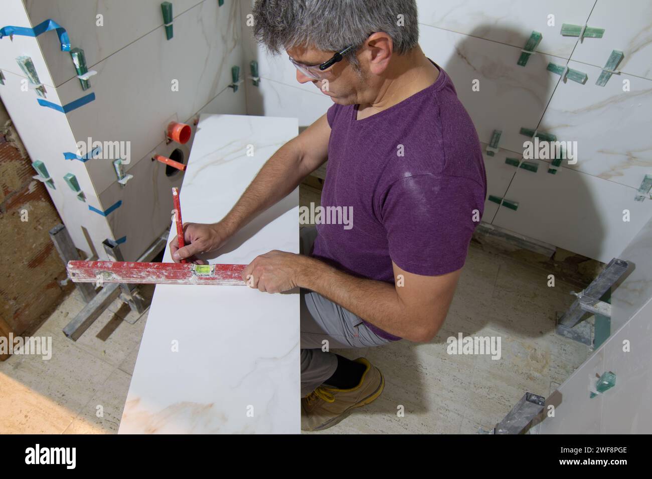 Tuile dans un petit espace mesurant et marquant une tuile pour l'installation d'un mur de tuile dans une rénovation de salle de bains. Concept de rénovation domiciliaire Banque D'Images
