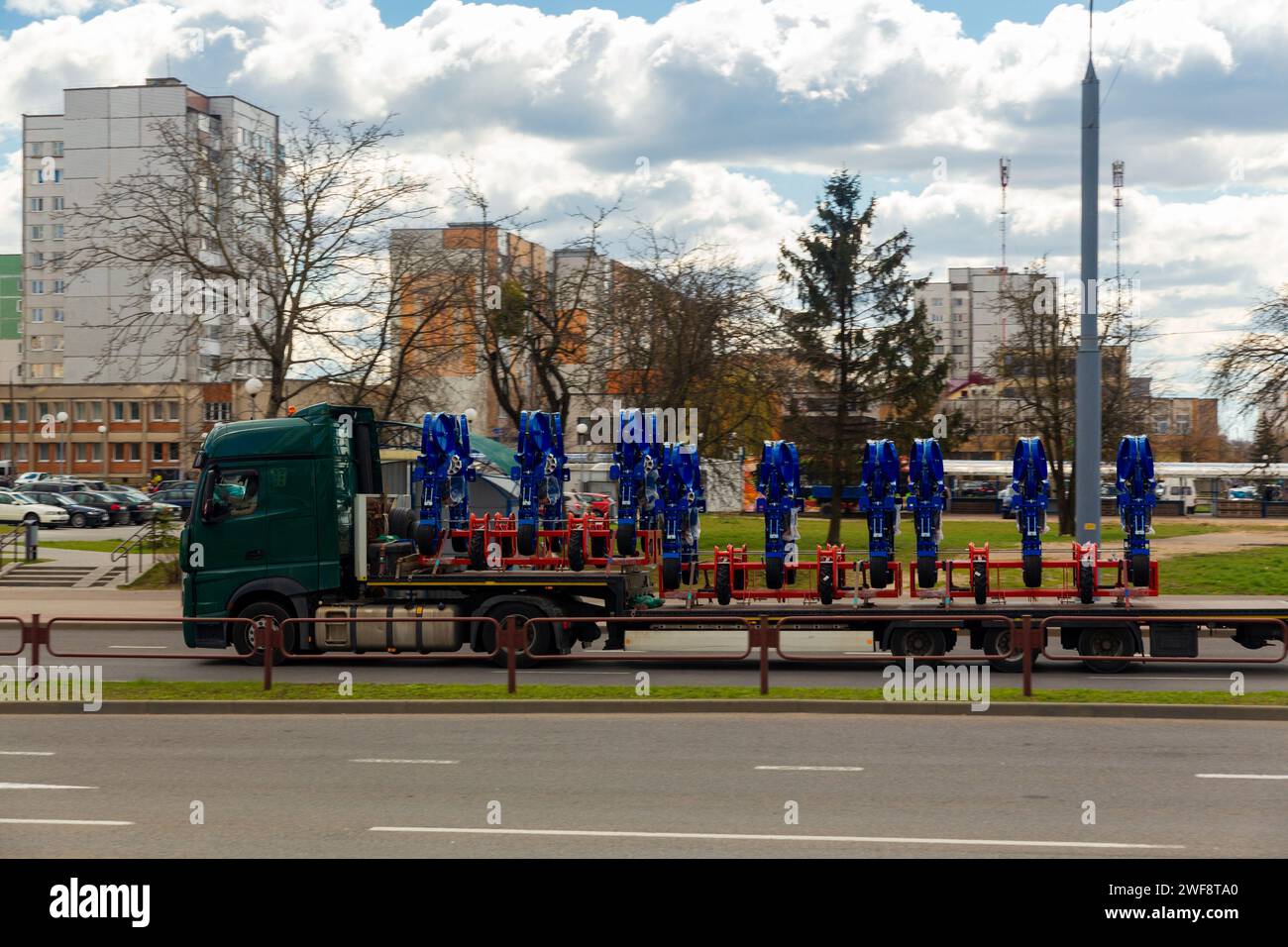 Transport de grandes machines agro-complexes pour cultiver et semer les cultures sur de longues remorques par camions le long de la rue dans la ville Banque D'Images