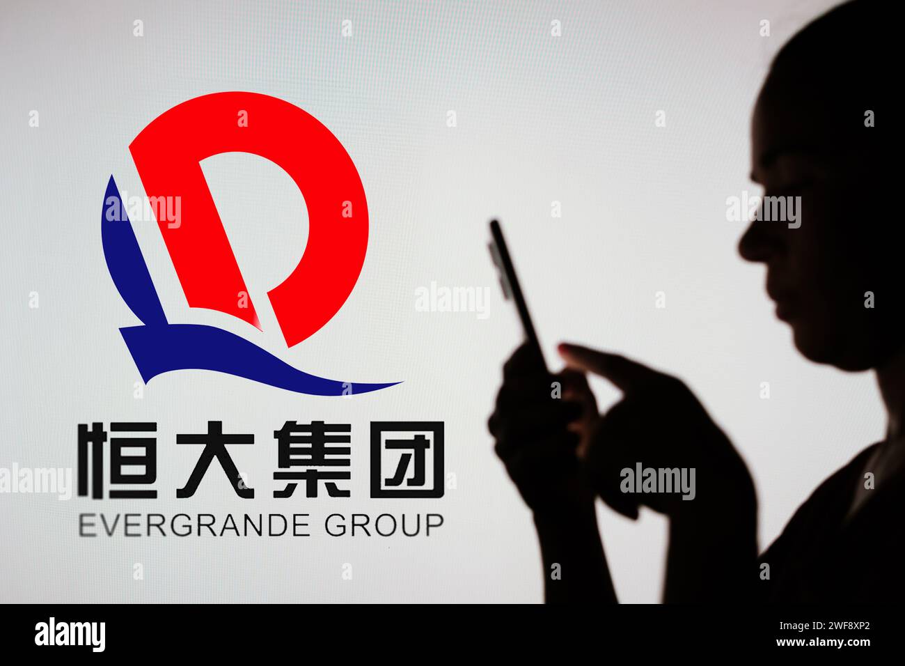 Brésil. 29 décembre 2023. Sur cette photo, la silhouette d'une femme tient un smartphone avec le logo Evergrande Real Estate Group en arrière-plan. (Image de crédit : © Rafael Henrique/SOPA Images via ZUMA Press Wire) USAGE ÉDITORIAL SEULEMENT! Non destiné à UN USAGE commercial ! Banque D'Images