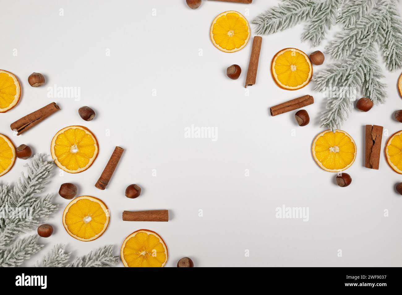 Composition de Noël, tranches d'orange séchées, branches de sapin, bâtonnets de cannelle, noisettes sur fond blanc. Noël, nouvel an, concept d'hiver. Banque D'Images