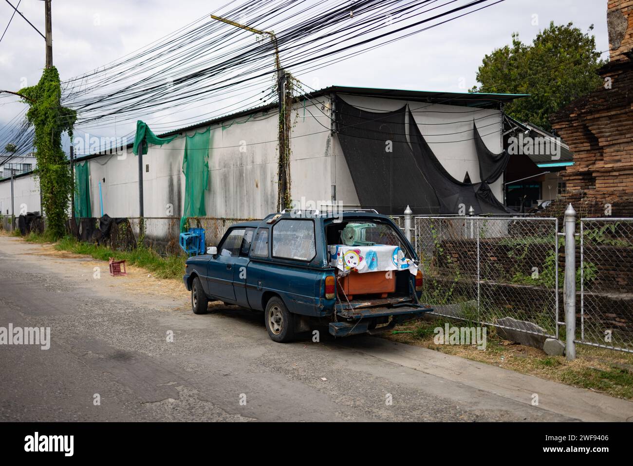 Une petite camionnette bleue est garée sur le côté d'une route urbaine très fréquentée, entourée de bâtiments et de circulation. Banque D'Images