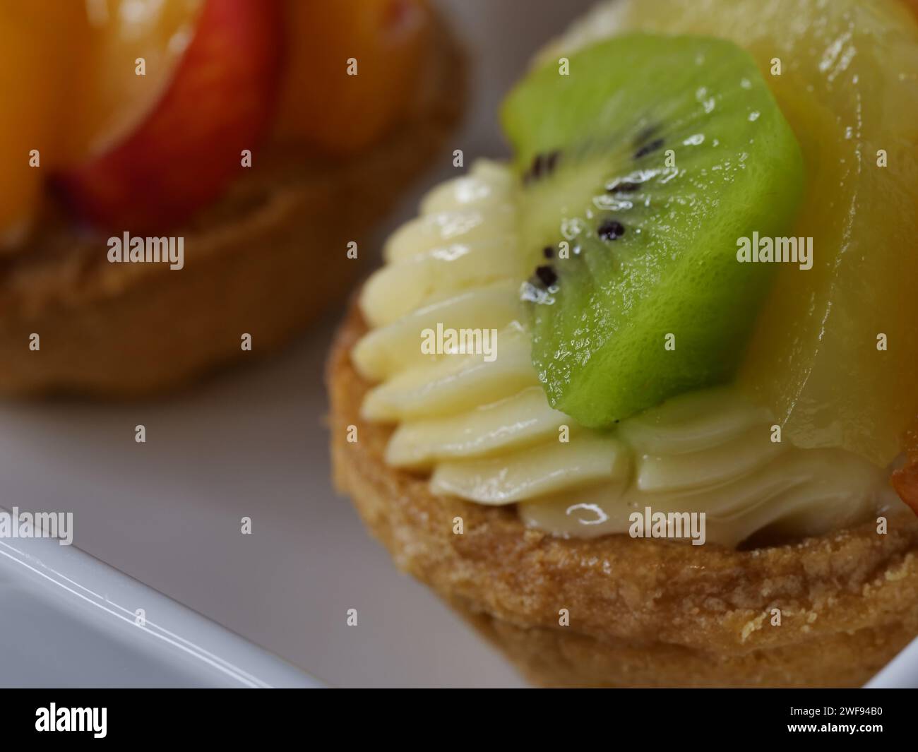 Une variété de desserts délicieux magnifiquement disposés sur un plat blanc immaculé, accompagnés d'un fruit vibrant et succulent Banque D'Images