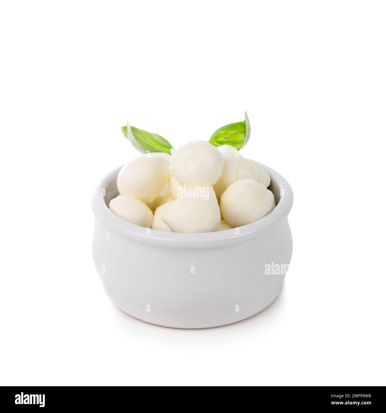 mini boules de fromage mozzarella dans un petit bol avec du basilic isolé sur fond blanc Banque D'Images